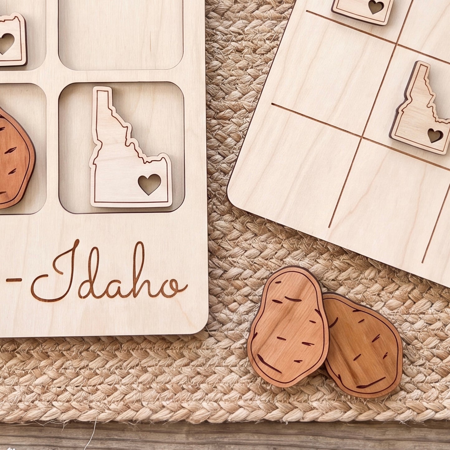 a wooden game board with a potato cutout and the word "Idaho" written on it. There are also two wooden potato cutouts on the ground.