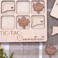 a wooden tic-tac game board with wooden pieces shaped like leaves and states, specifically Connecticut, placed on it.