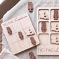 a wooden tic-tac game board and several wooden tiles shaped like lobsters, with the word "TIC-TAC-LOUISIANA" written on the board.