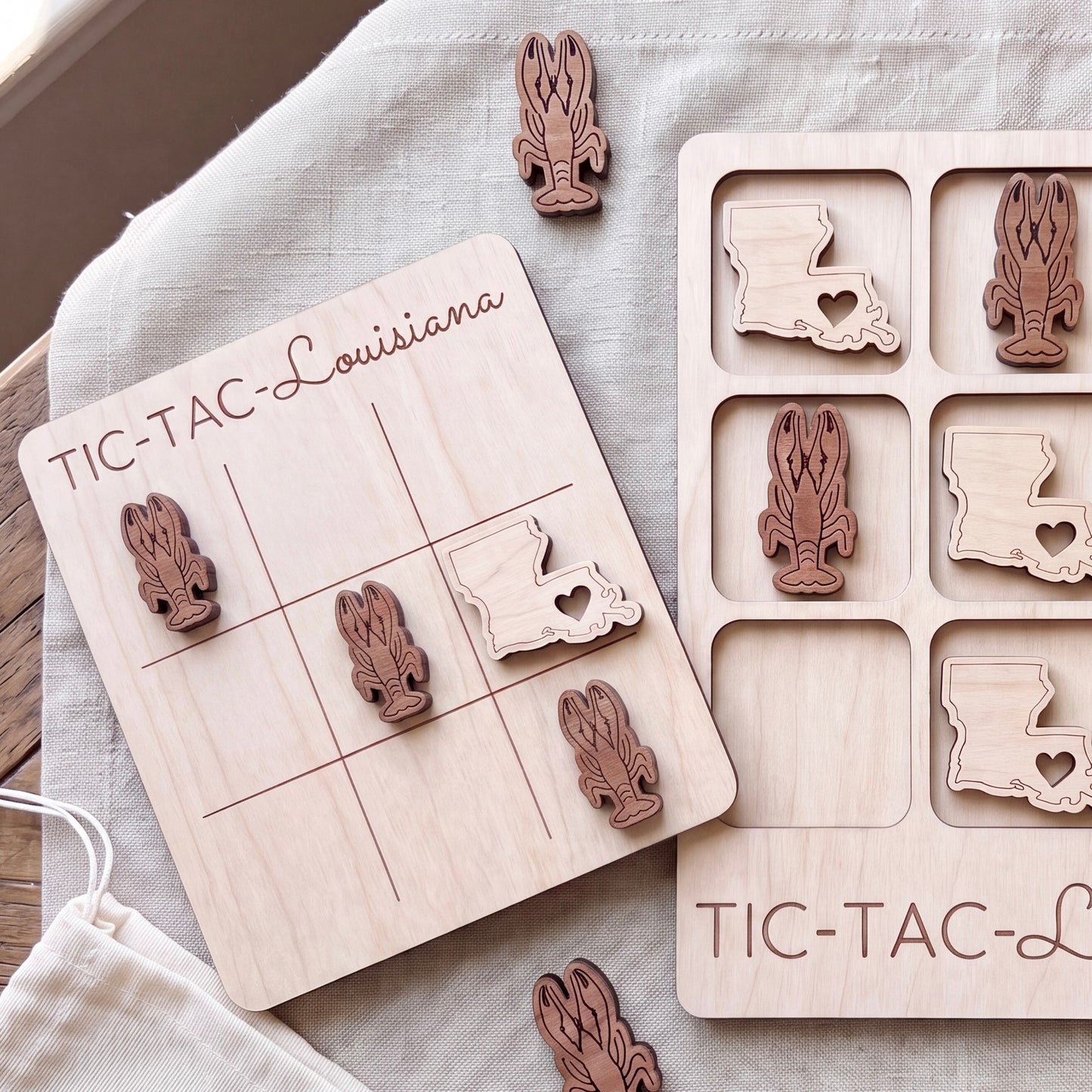 a wooden tic-tac game board and several wooden tiles shaped like lobsters, with the word "TIC-TAC-LOUISIANA" written on the board.