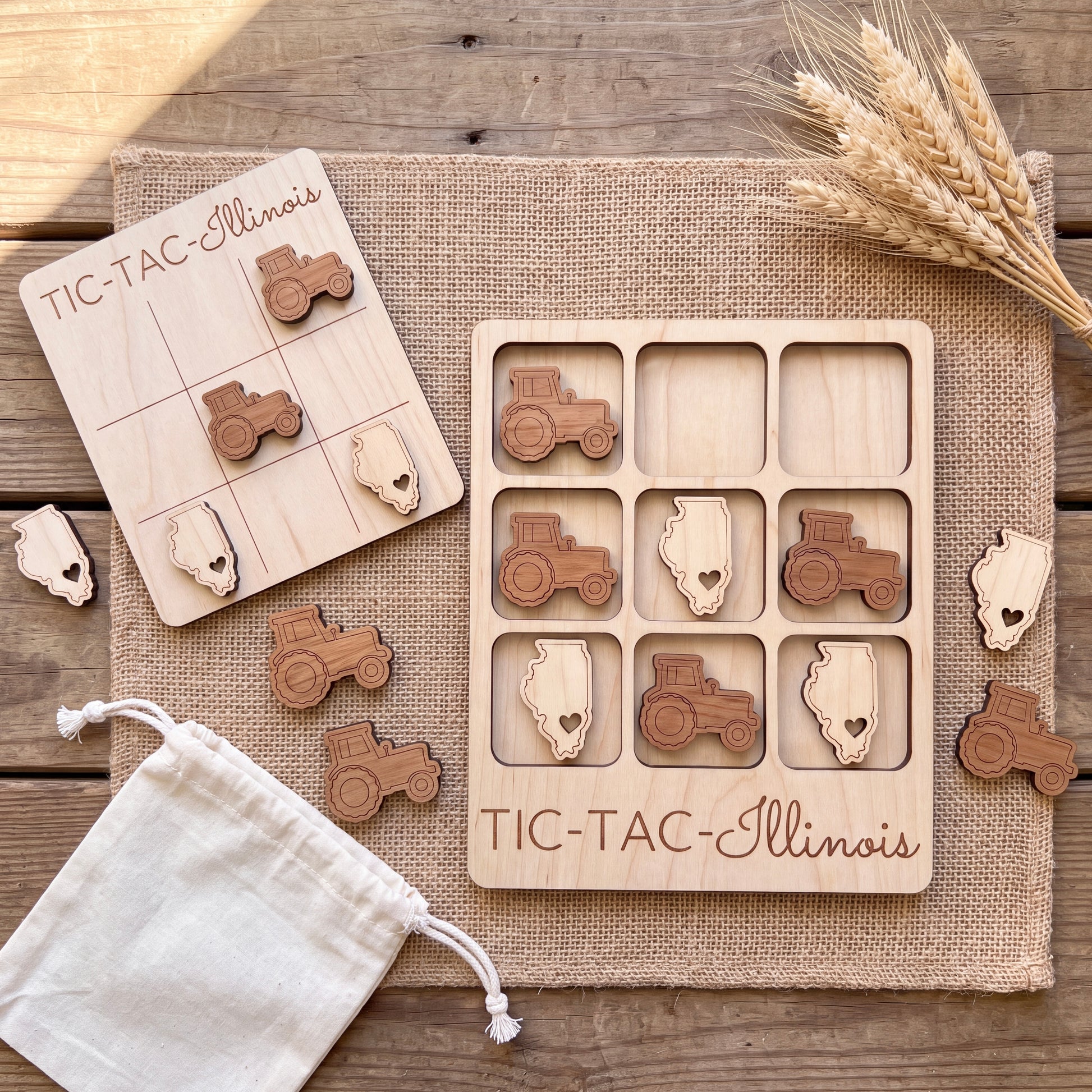 a wooden tic-tac game set with tractor and corn-themed pieces, placed on a burlap cloth.
