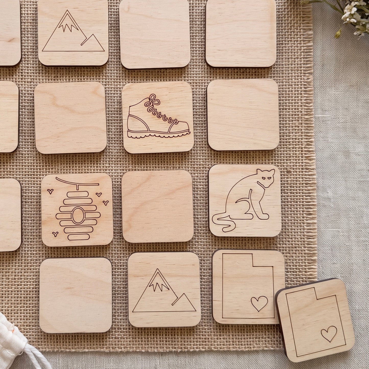 a collection of wooden coasters or tiles with various symbols and designs, including a mountain, a shoe, a cat, and other abstract shapes.