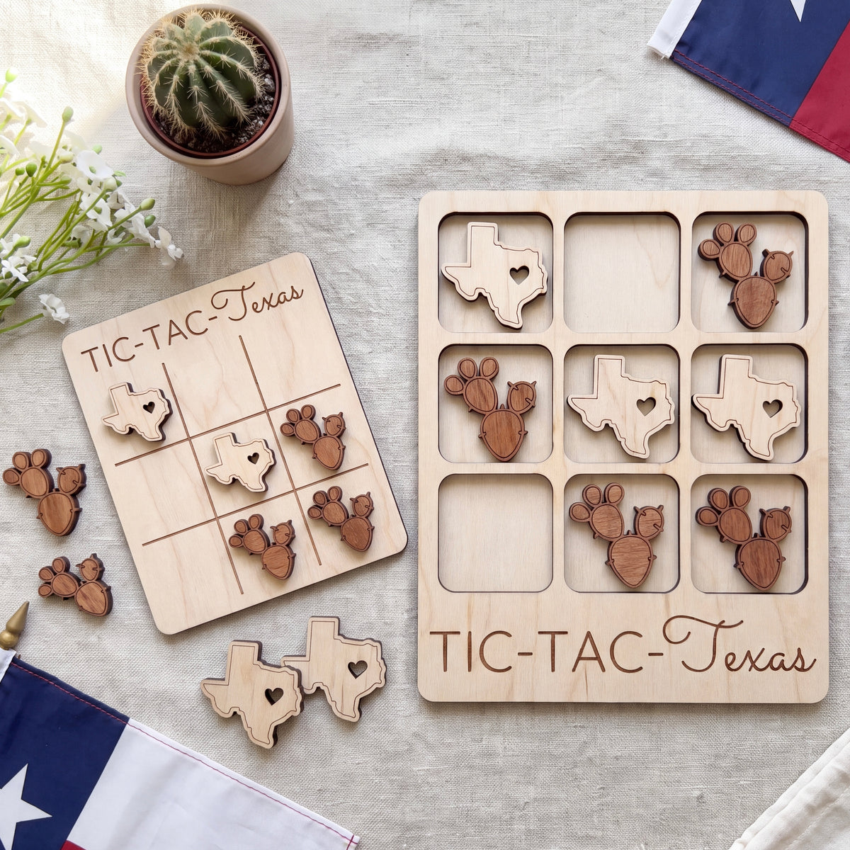 a wooden Tic-Tac-Texas game board and several wooden tiles shaped like the state of Texas, along with a potted cactus plant and a flag.