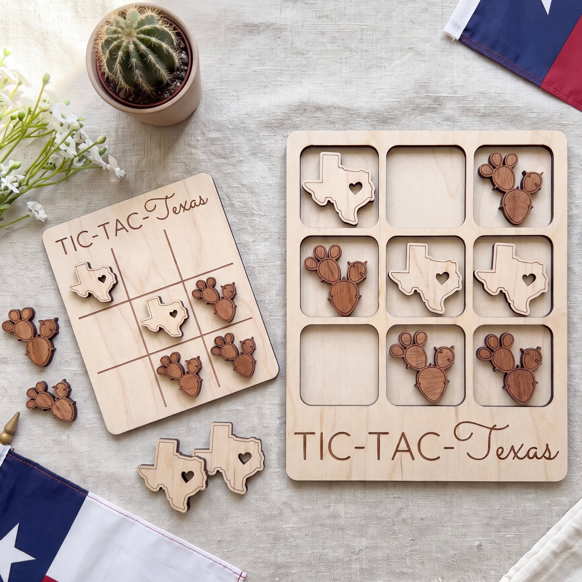 a wooden Tic-Tac-Texas game board and several wooden tiles shaped like the state of Texas, along with a potted cactus plant and a flag.