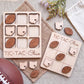 a wooden tic-tac game with Ohio state symbols, a football, and some flowers on a beige cloth.
