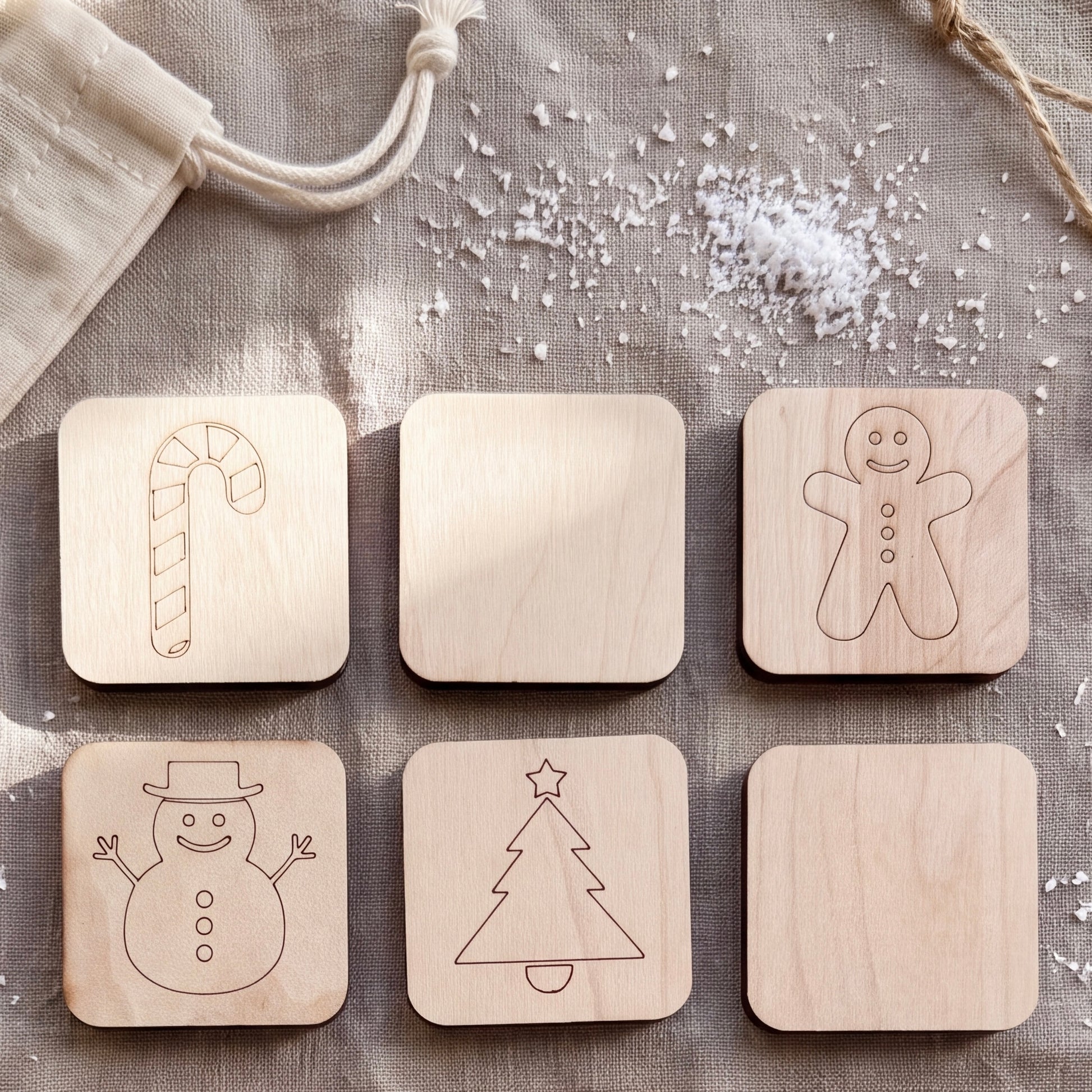 a collection of six wooden coaster-shaped objects, each with a different holiday-themed design. The coasters include a candy cane, a gingerbread man, a snowman, a Christmas tree, a snowman, and a snowman.
