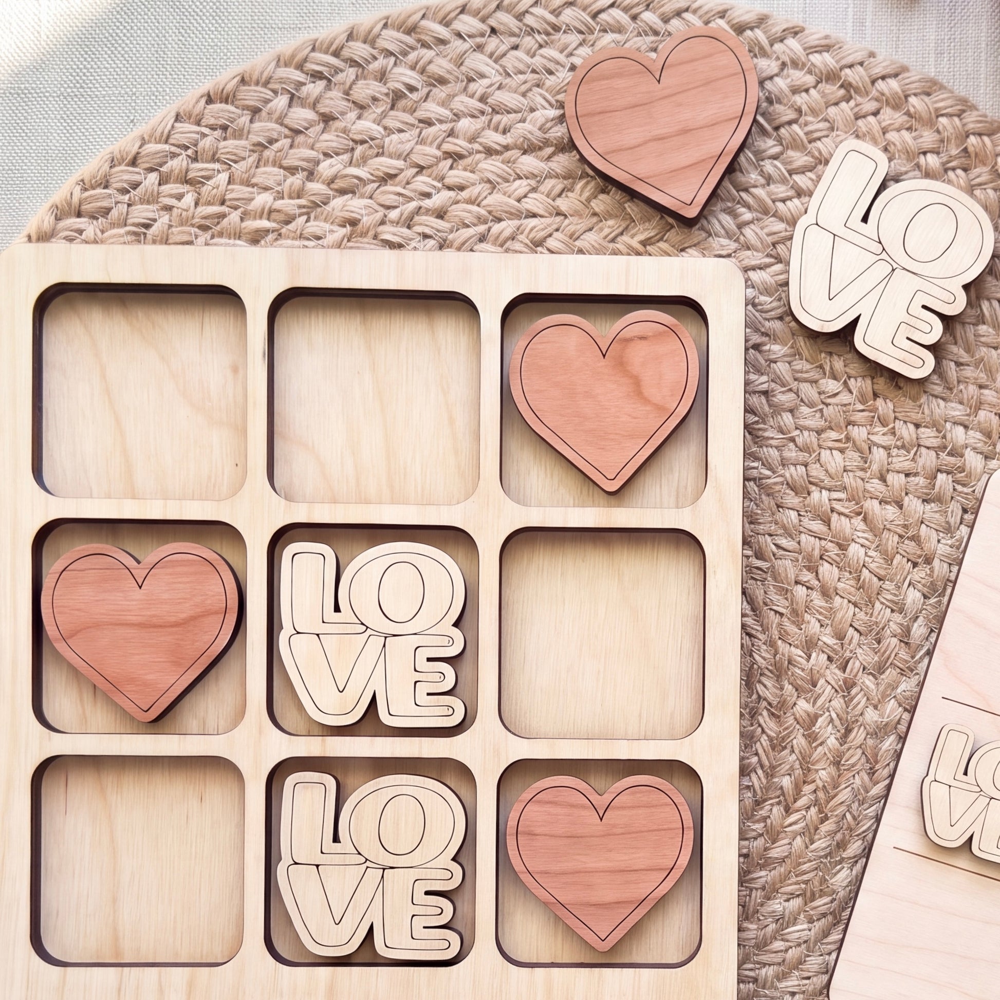 a wooden tic-tac-toe board with the word "LOVE" written on it, along with several wooden heart-shaped cutouts.
