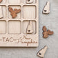 a wooden game board with a tic-tac game design, decorated with wooden game pieces shaped like moose heads and hearts.