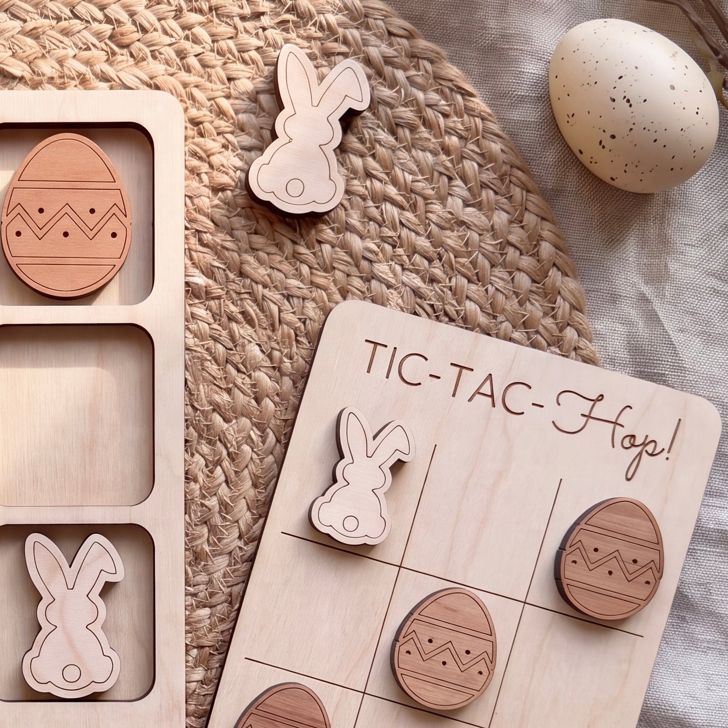 a wooden Easter-themed game board with wooden Easter eggs and a wooden bunny. The game board has the text "TIC-TAC-HOP!" written on it.