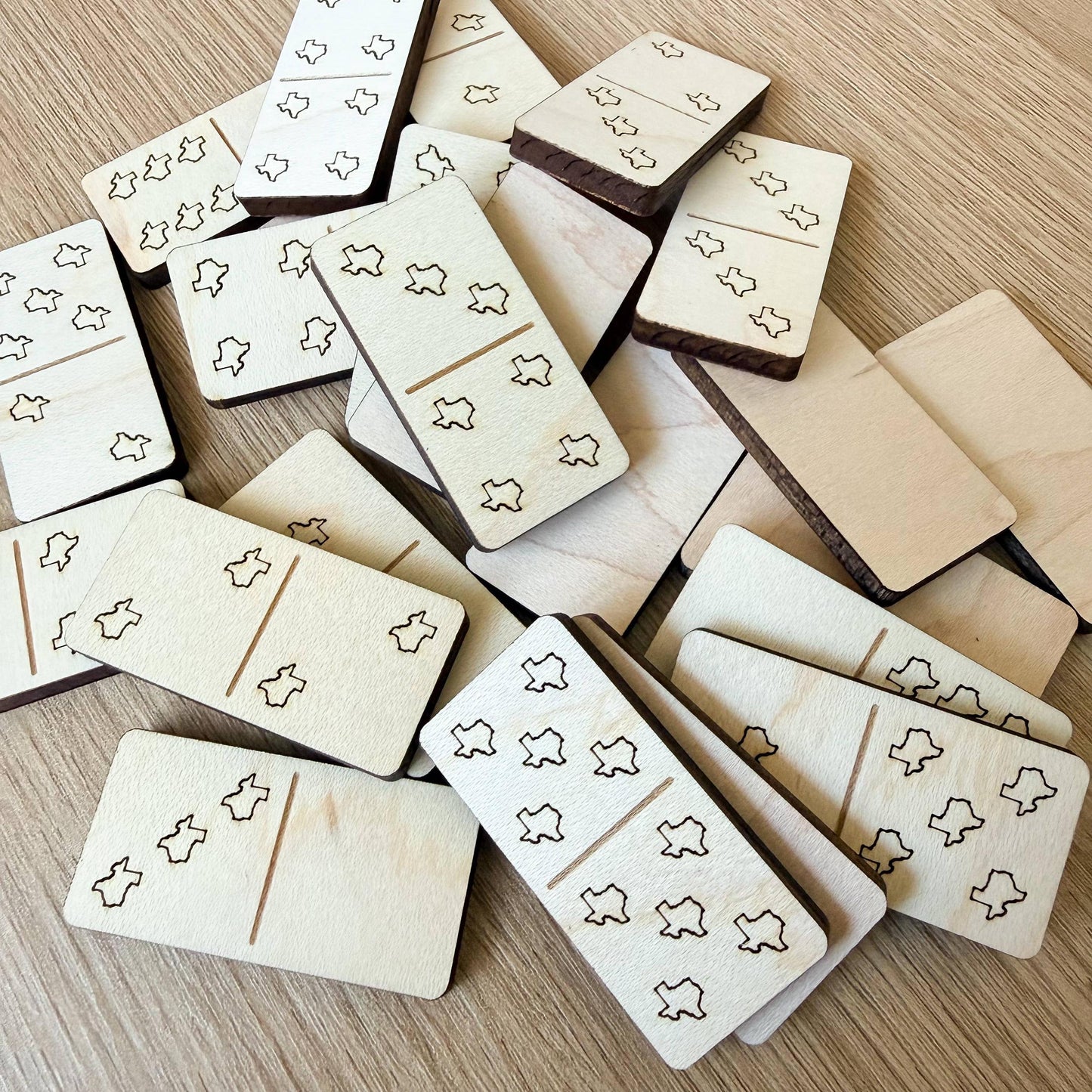a collection of wooden dominoes with various designs and patterns on them, scattered on a wooden surface.