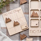 a wooden tic-tac game board with the word "Oregon" written on it, along with several wooden tic-tac pieces shaped like mountains.