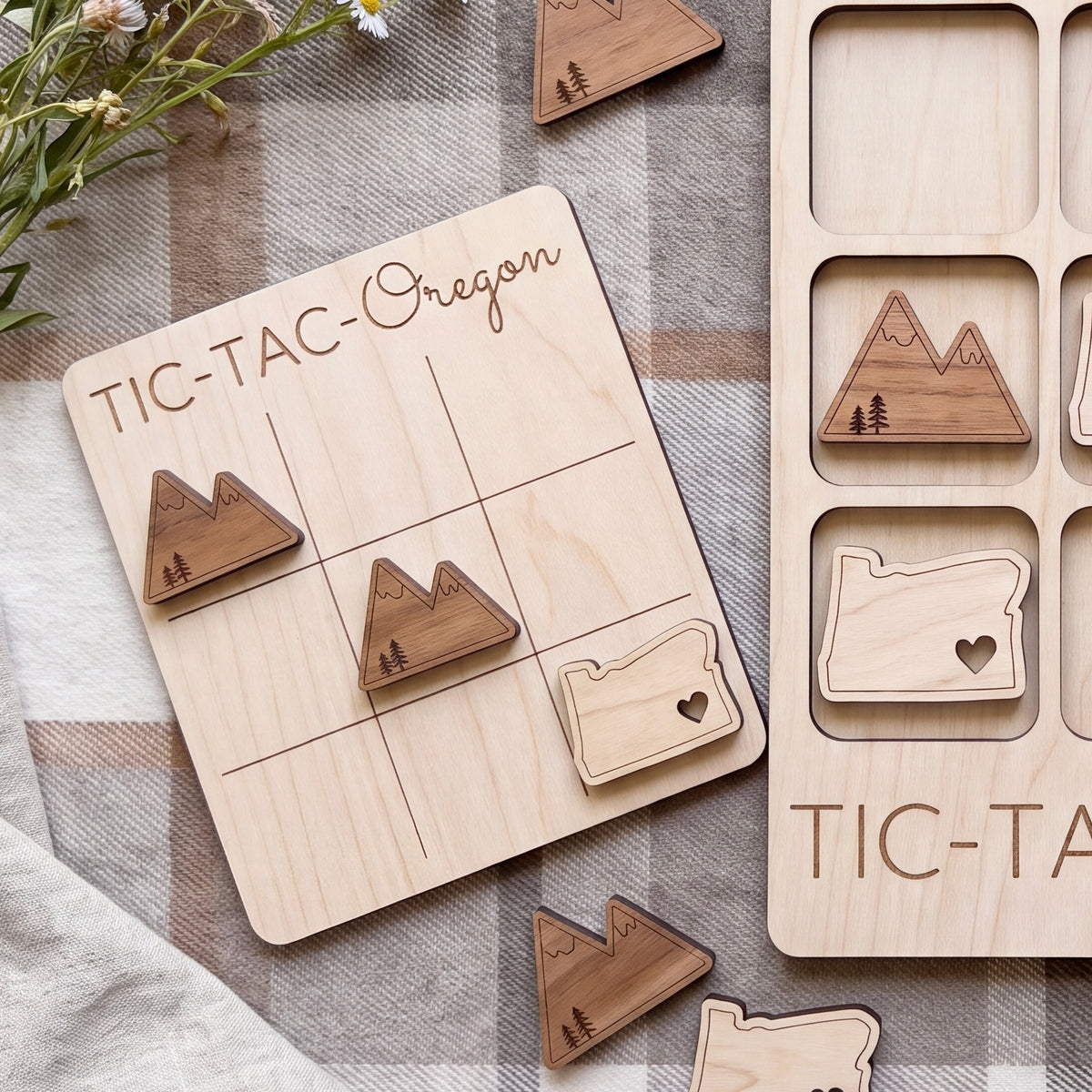 a wooden tic-tac game board with the word "Oregon" written on it, along with several wooden tic-tac pieces shaped like mountains.