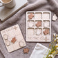 a wooden tic-tac game set with coffee cup tiles and wooden coffee cups, along with a mug and some books.