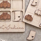 a wooden tic-tac-toe board with wooden pieces shaped like race cars and a wooden piece with a heart shape, both placed on a wooden surface.