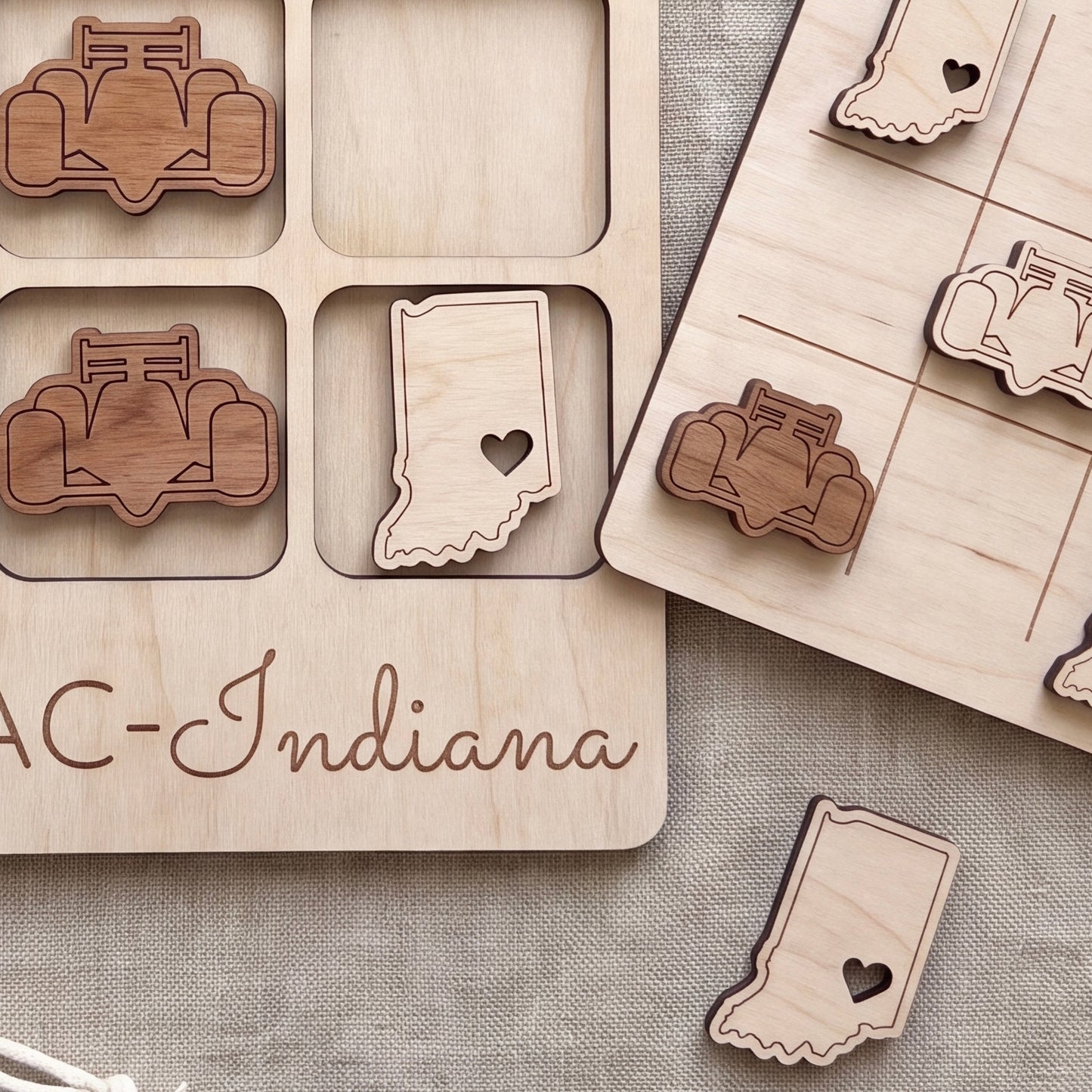 a wooden tic-tac-toe board with wooden pieces shaped like race cars and a wooden piece with a heart shape, both placed on a wooden surface.