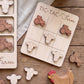 a wooden tic-tac farm game board with tractor and cow tiles, along with a wooden chicken and tractor toy set on a wooden surface.