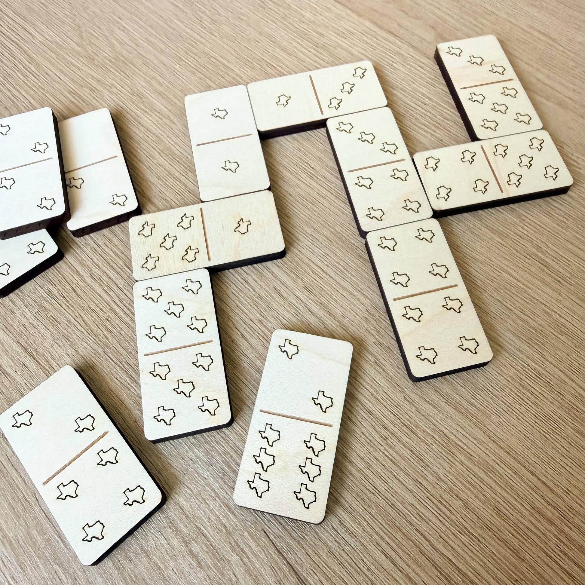 several wooden dominoes with a repeating pattern of small black shapes, arranged on a wooden surface.