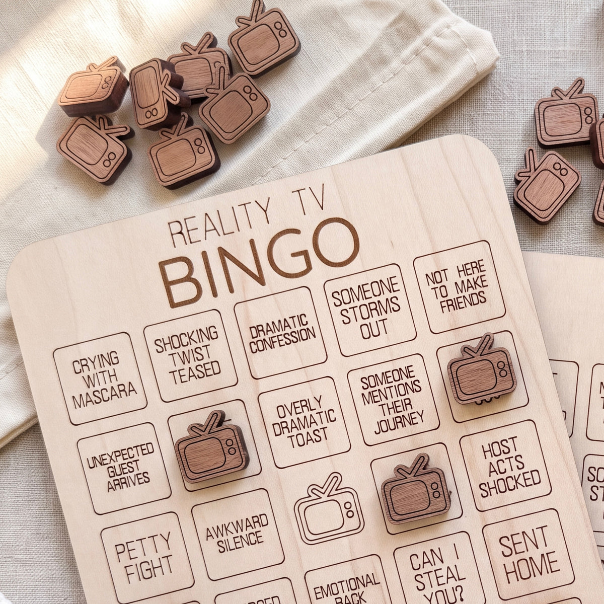 a wooden bingo game board with various phrases and television-themed stickers.