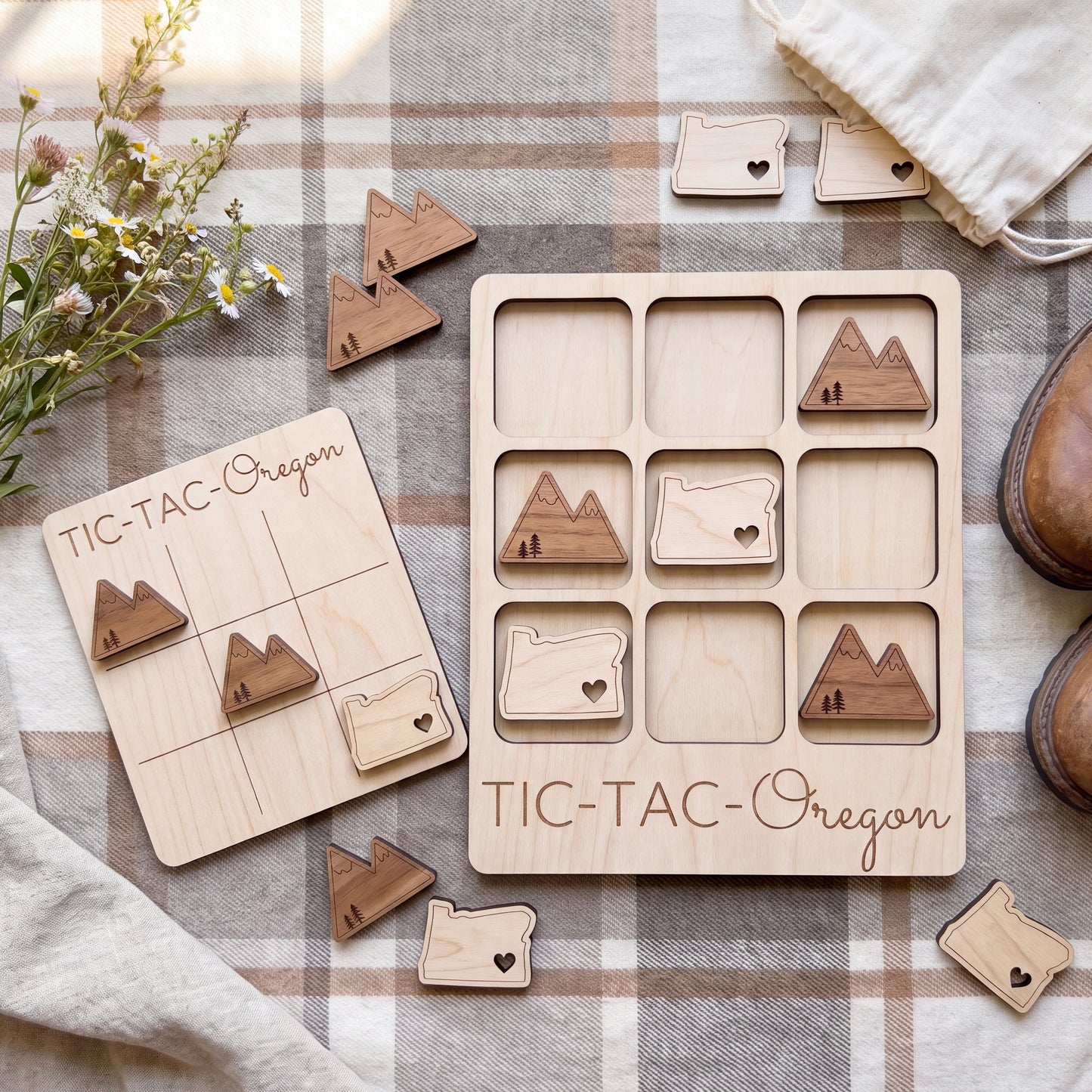 a wooden tic-tac game with Oregon state shapes, placed on a plaid cloth. The game appears to be made of wood and has a rustic, handmade aesthetic.