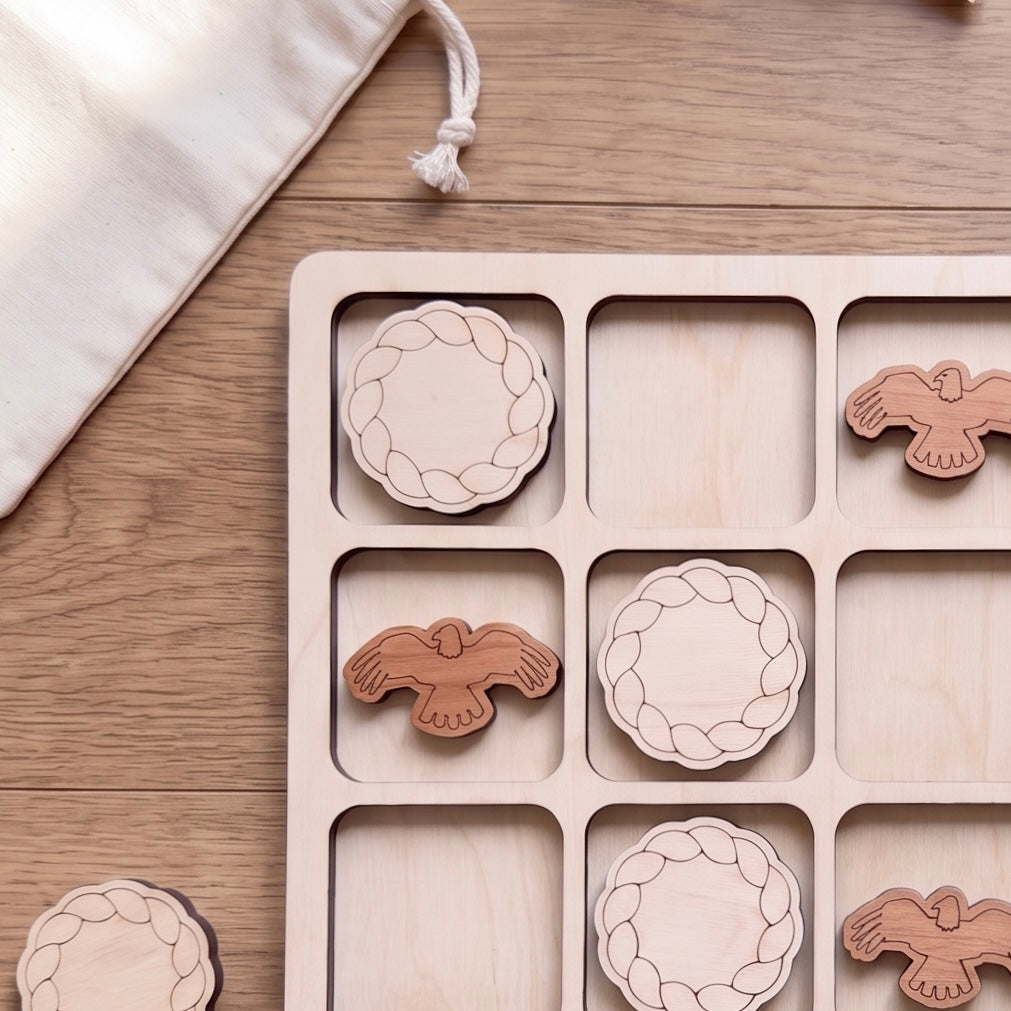 A wooden tic-tac game with wooden pieces in the shape of birds, arranged in a grid on a wooden surface.