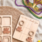 a wooden tic-tac game with masks and beads, suggesting a festive or celebratory theme.