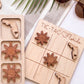 a wooden tic-tac game board with wooden pieces shaped like suns and a Florida state flag, along with a pair of sunglasses and a palm leaf.