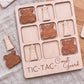 A wooden tic-tac game board with wooden pieces shaped like lighthouses and anchors, labeled "Coast Guard".