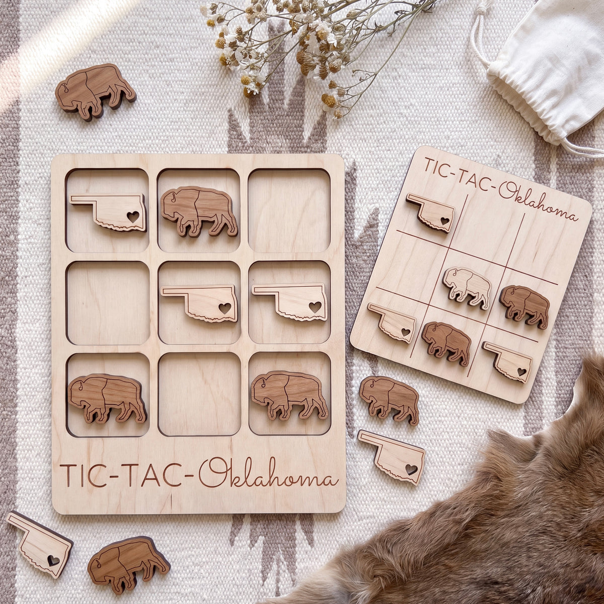 a wooden game board labeled "TIC-TAC-Oklahoma" and several wooden pieces shaped like bison, likely representing the state of Oklahoma.