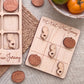 a wooden tic-tac game board with wooden pieces shaped like the state of New Jersey, as well as a wooden bowl containing tomatoes and a woven placemat.