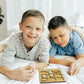 two young boys laying on a bed playing with a game