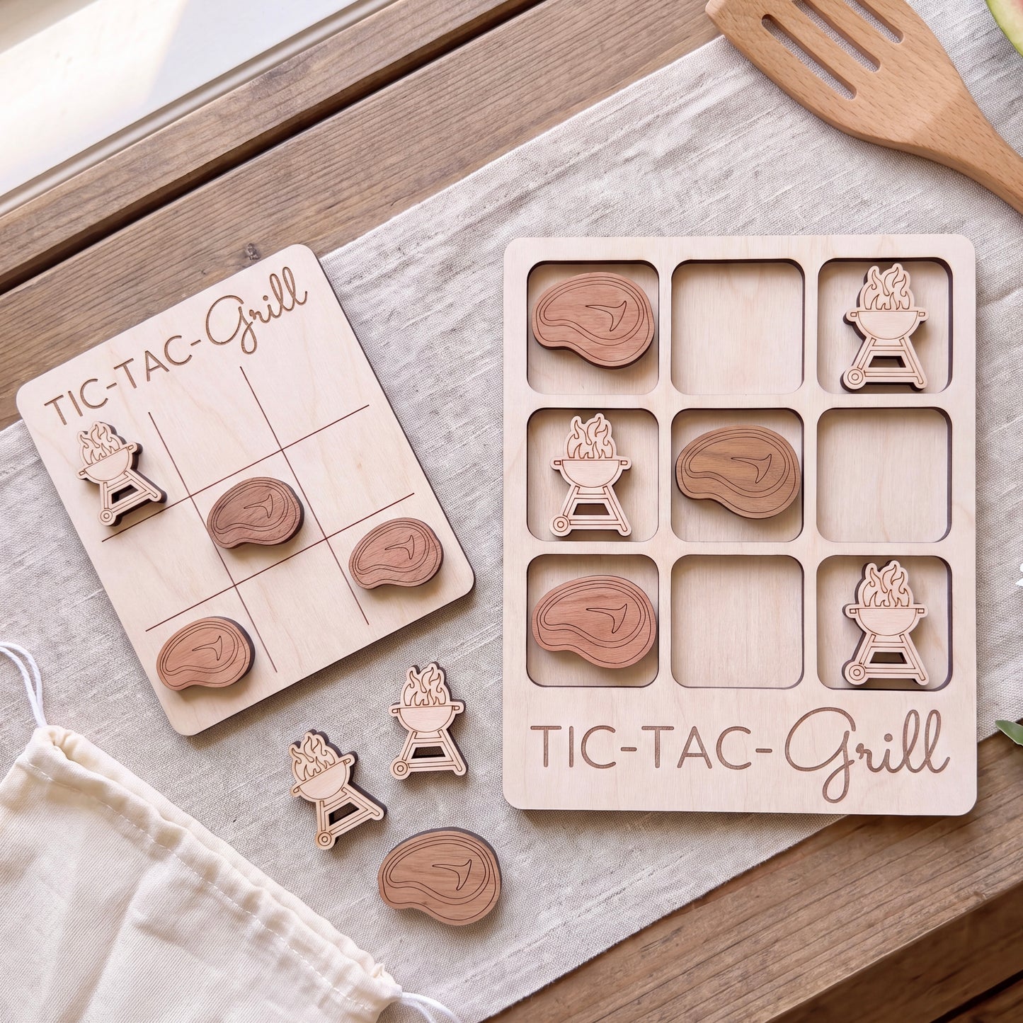 a wooden Tic-Tac-Grill game board and several wooden pieces shaped like grilled meat, arranged on a wooden surface.