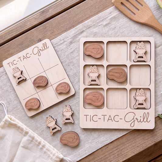 a wooden Tic-Tac-Grill game board and several wooden pieces shaped like grilled meat, arranged on a wooden surface.