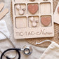 a wooden tic-tac-toe game with a stethoscope and a heart-shaped token, along with other medical-themed items such as a stethoscope and a white cloth.