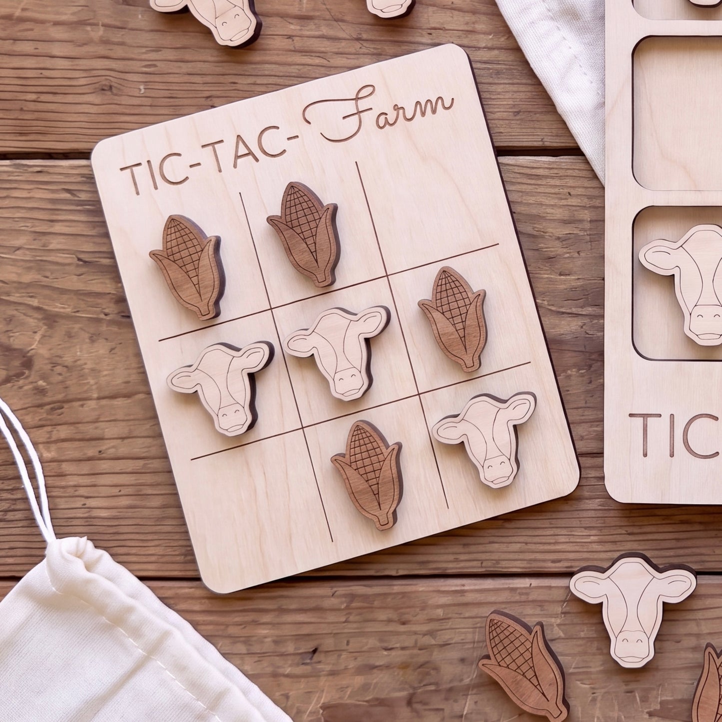 a wooden tic-tac game board with wooden pieces shaped like cows and corn, arranged in a grid on the board.