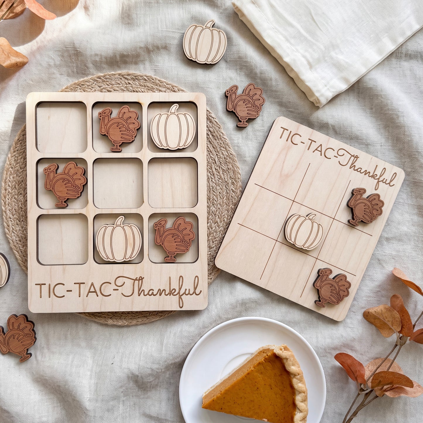 a wooden Thanksgiving-themed game with a pumpkin and turkey design, along with a white plate with a slice of pumpkin pie.