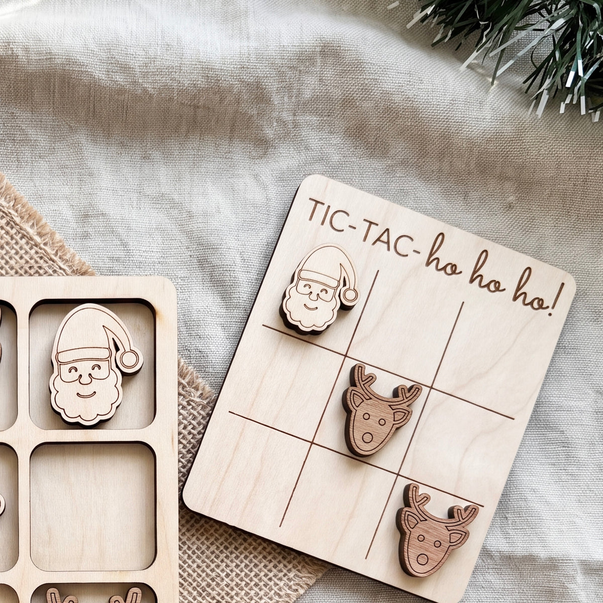 A wooden tic-tac game with a Santa Claus and reindeer figure, along with a wooden sign that says "TIC-TAC-ho ho ho!".