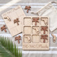 a wooden Tic-Tac-Florida game board with wooden pieces shaped like palm trees, placed on a striped towel.