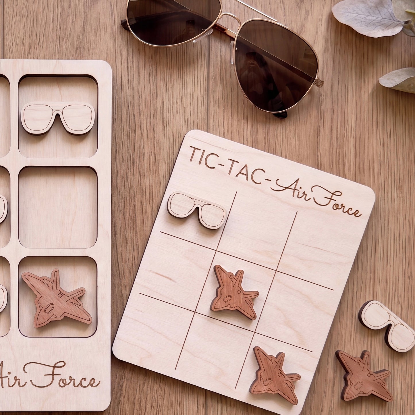 a wooden tic-tac game board labeled "TIC-TAC-AIR FORCE" with wooden airplane and sunglasses pieces attached to it.