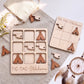a wooden tic-tac game set with wooden pieces shaped like the state of Oklahoma, along with a dreamcatcher and some flowers.