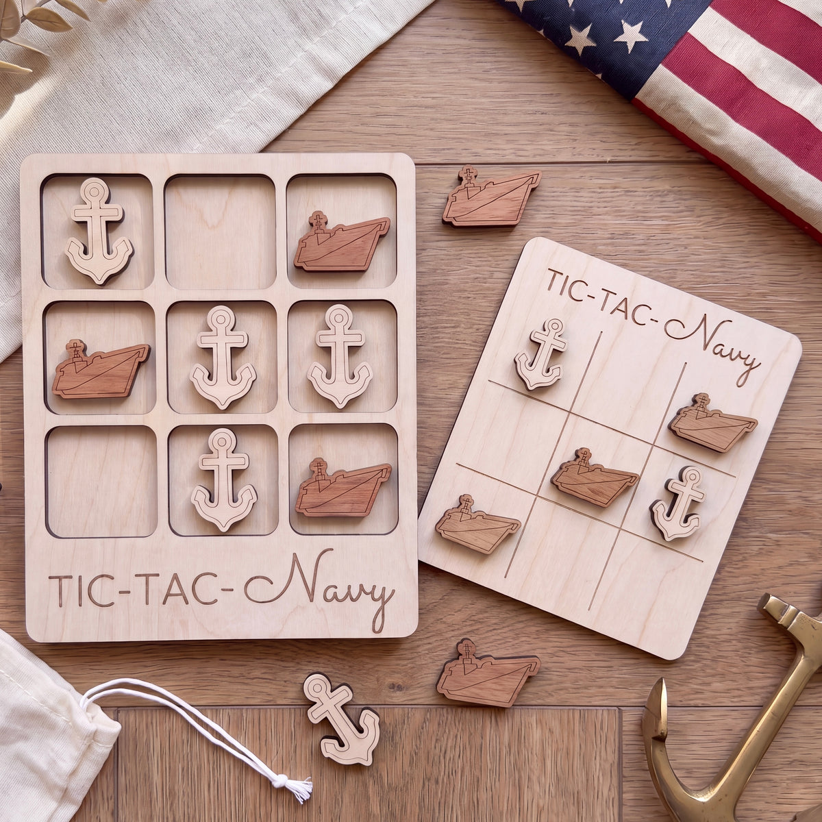 a wooden tic-tac-toe game board labeled "TIC-TAC-Navy" and a set of wooden tic-tac pieces with anchors on them, placed on a wooden surface.