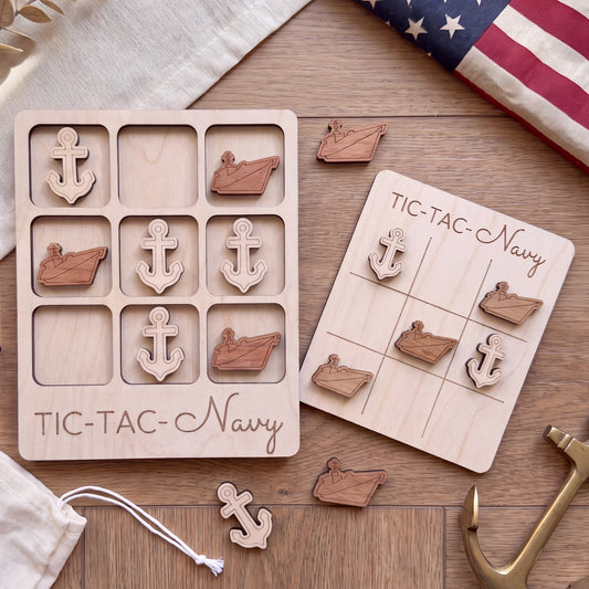 a wooden tic-tac-toe game board labeled "TIC-TAC-Navy" and a set of wooden tic-tac pieces with anchors on them, placed on a wooden surface.