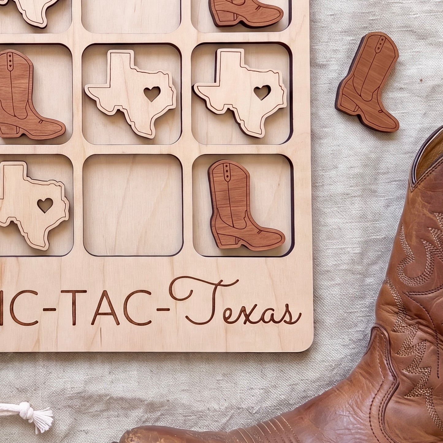 a wooden game board with a Texas state map cut out, along with wooden boot cutouts, and a pair of brown leather boots.