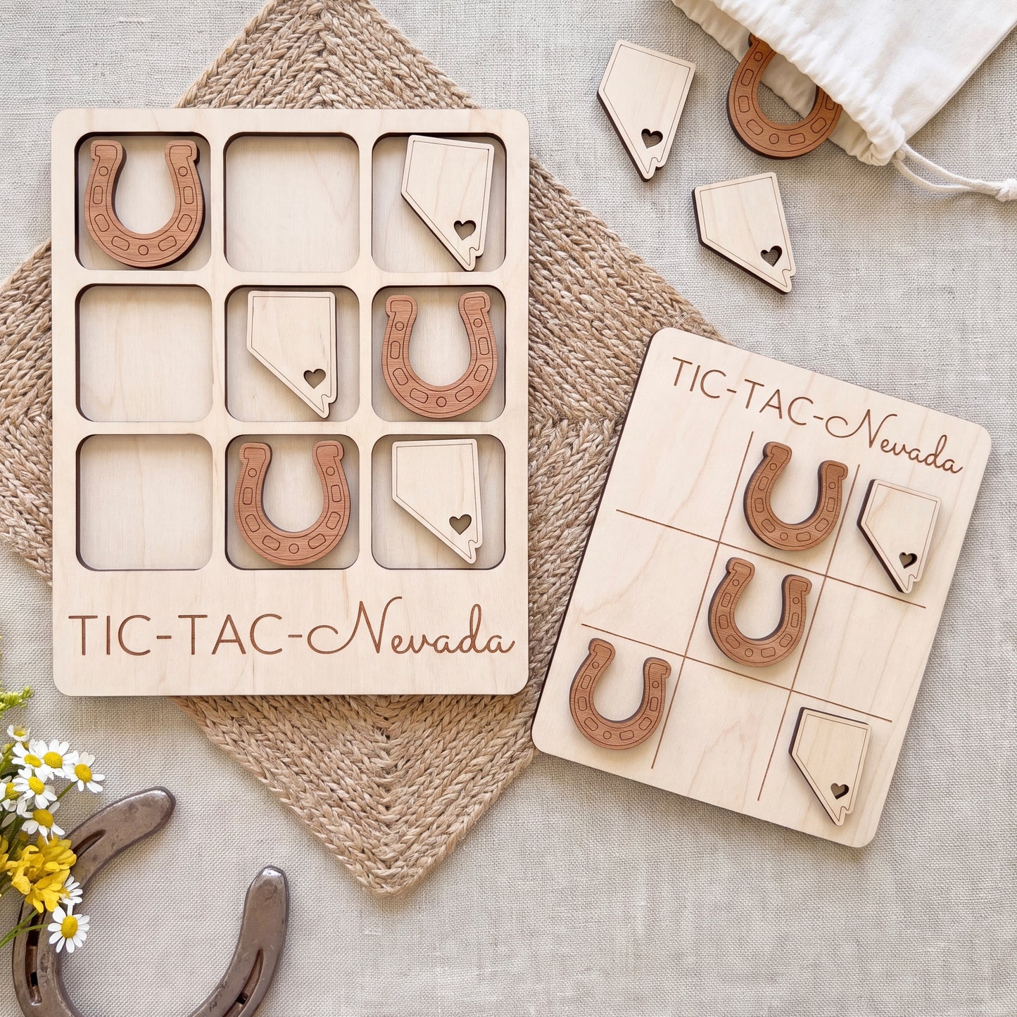 a wooden tic-tac game set with wooden pieces shaped like horseshoes, labeled "TIC-TAC-Nebraska". The game is placed on a beige cloth, and there are some additional wooden pieces scattered around the game.