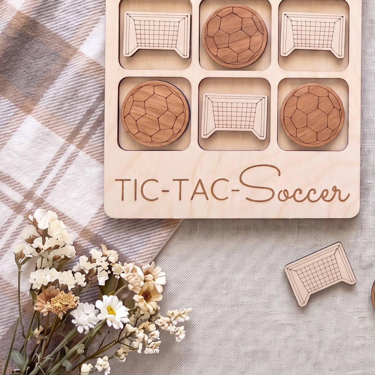 a wooden tic-tac-toe game with soccer ball tiles, a floral arrangement, and a wooden sign that says "TIC-TAC-Soccer".