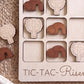 A wooden tic-tac game board with wooden pieces featuring religious symbols, such as crosses and wreaths, arranged in a grid pattern.