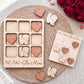 a wooden tic-tac game with the words "Love" written on it, along with wooden hearts. The game is placed on a woven placemat, and there are also some wooden hearts scattered around the game.