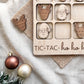 a wooden tic-tac game with wooden pieces shaped like Santa Claus and reindeer, along with a Christmas ornament and a burlap cloth.