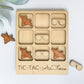A wooden tic-tac game board with various airplane and sunglasses cutouts, along with a pair of sunglasses placed on the right side of the board.