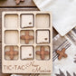 A wooden tic-tac game board with wooden pieces shaped like state flags, labeled "New Mexico", placed on a wooden surface.