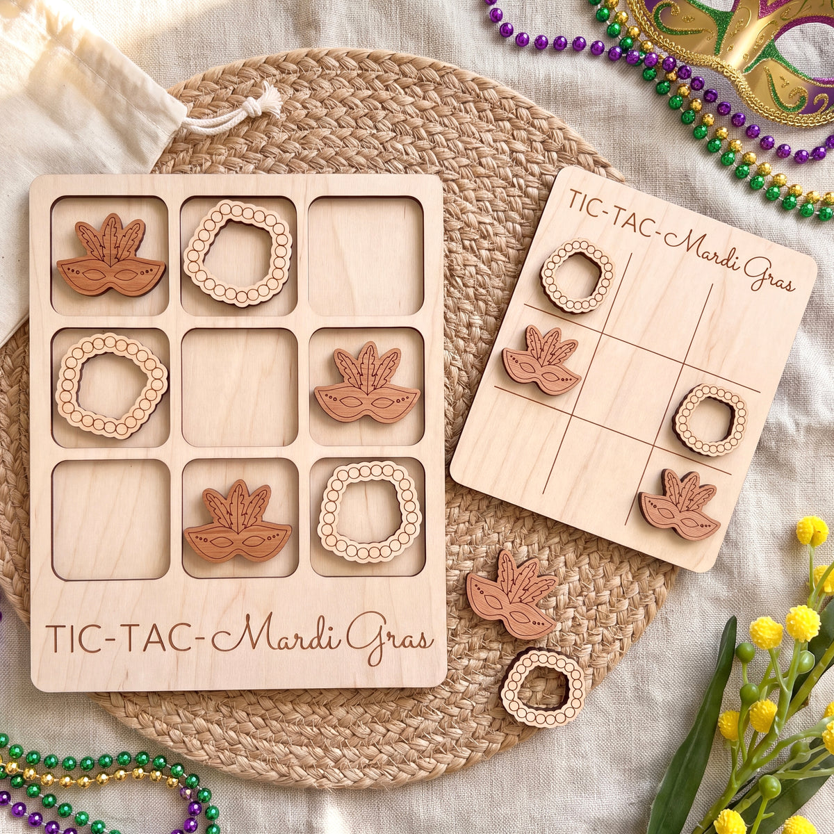 a wooden tic-tac game set with Mardi Gras beads and masks, arranged on a woven placemat.